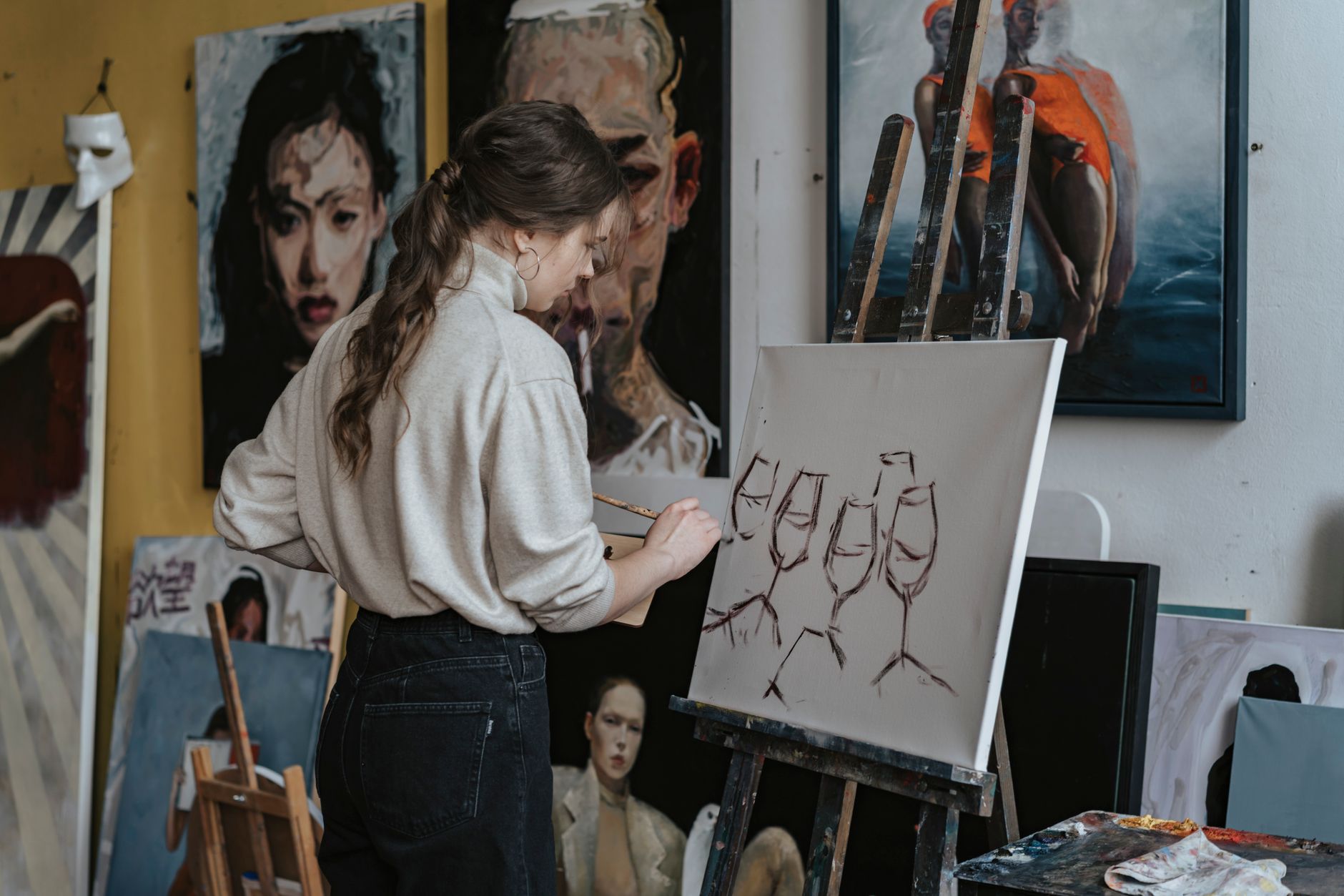 A woman artist paints wine glasses on canvas in a creative studio setting in Long Beach, CA